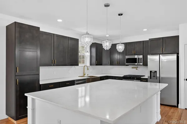 a kitchen with granite countertop a sink a center island stainless steel appliances and cabinets