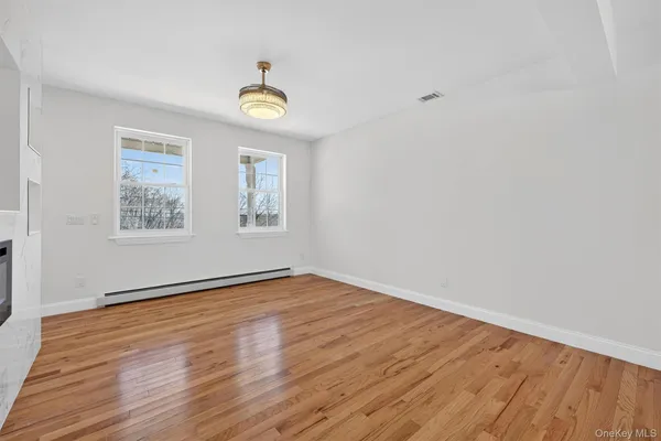 a view of an empty room with window and wooden floor