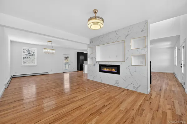 a view of empty room with wooden floor and kitchen view