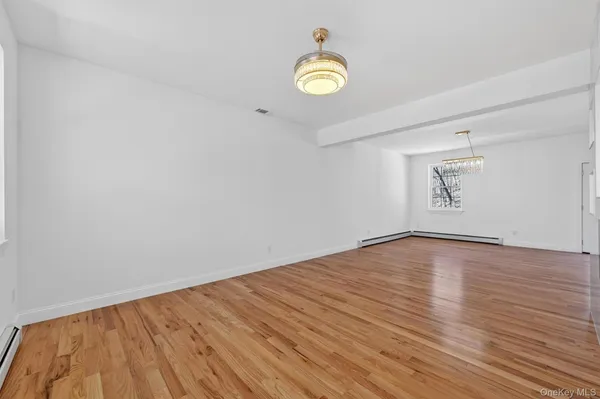a view of empty room with wooden floor and window