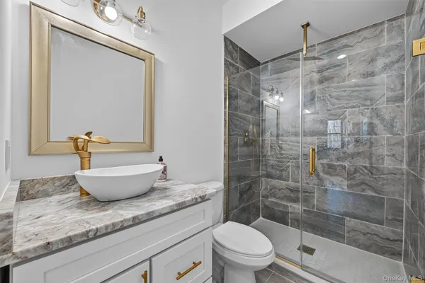 a bathroom with a granite countertop sink a toilet and shower