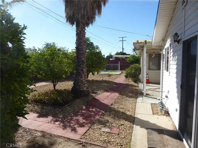 a view of a house with a small yard and large tree
