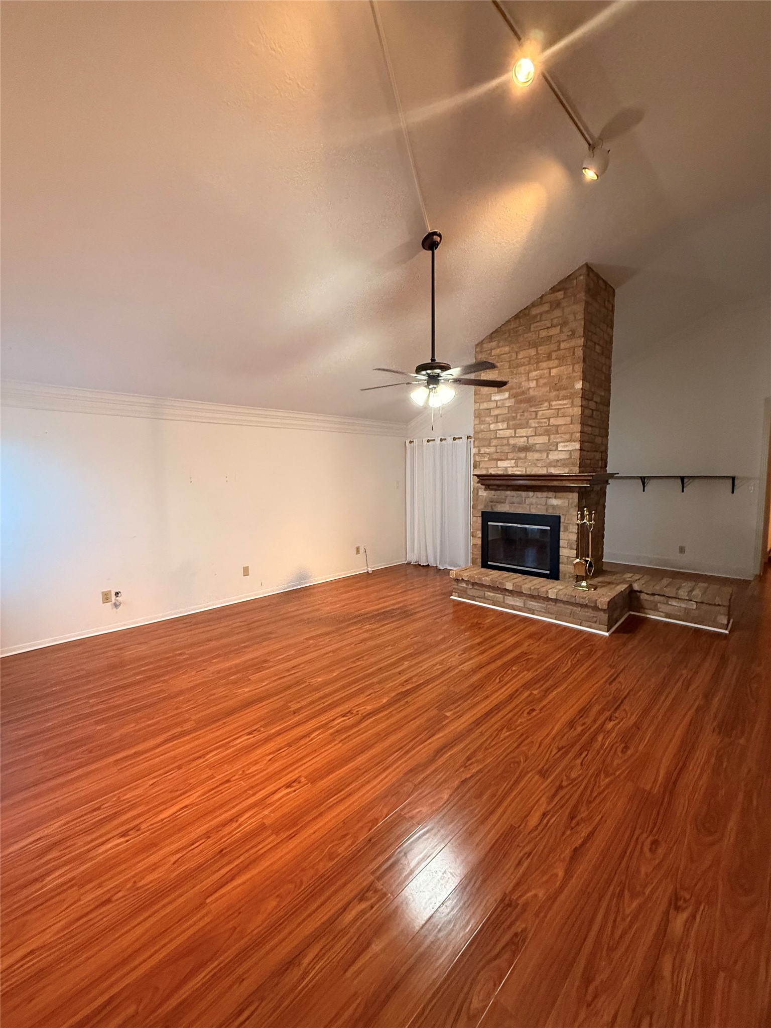 an empty room with wooden floor fireplace and window