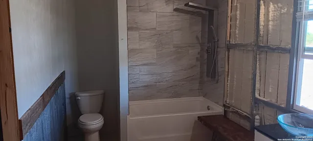 a bathroom with a granite countertop bathtub shower and toilet