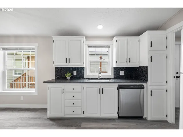 a kitchen with stainless steel appliances white cabinets and a window