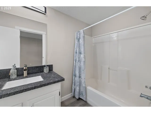 a bathroom with a granite countertop sink a mirror and a bathtub