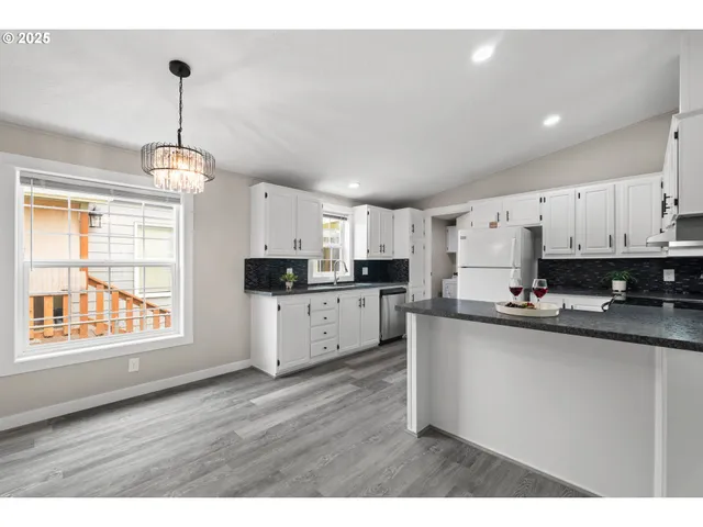 a kitchen with stainless steel appliances granite countertop a sink a stove a refrigerator and white cabinets