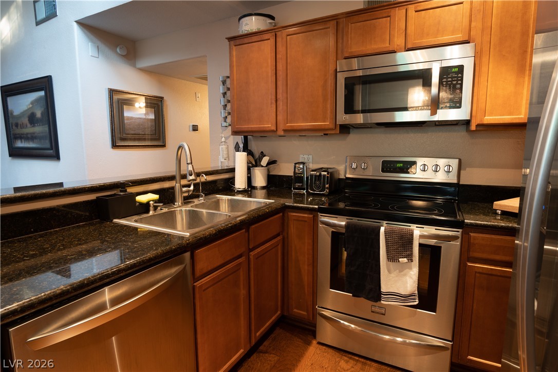 9325 West Desert Inn Road, Unit 264 Las Vegas, NV 89117 - Photo 3 of 10 Rich wood cabinetry and dark stone countertops create a classic culinary space with hardwood flooring.