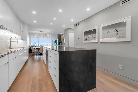 a large white kitchen with stainless steel appliances granite countertop a sink and dishwasher a stove with wooden floor