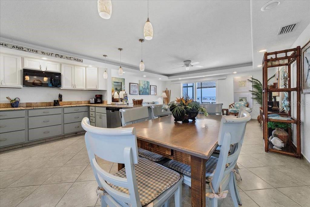 6154 Midnight Pass Road, Unit 104 Sarasota, FL 34242 - Photo 5 of 11 a kitchen with a table chairs refrigerator and microwave