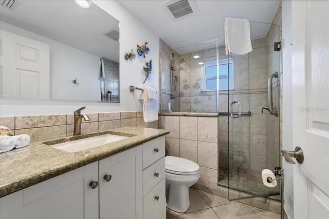 a bathroom with a granite countertop sink a toilet and shower