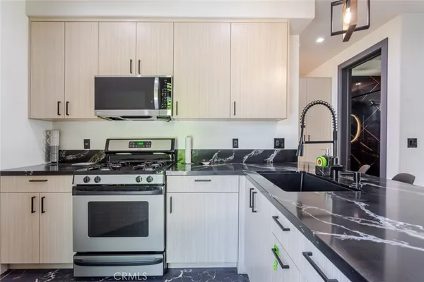 a kitchen with stainless steel appliances granite countertop a stove a sink and a microwave