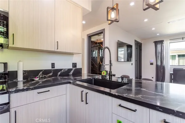 a kitchen with granite countertop a sink a counter top space and cabinets