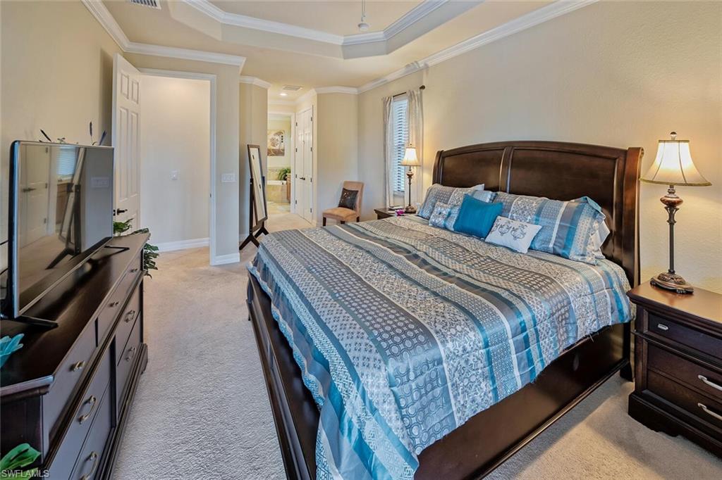 9415 Piacere Way Naples, FL 34113 - Photo 13 of 35 a bedroom with a bed and a flat tv screen on a dresser