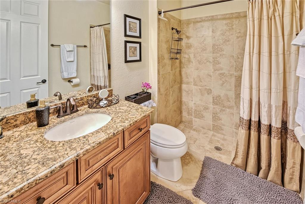 9415 Piacere Way Naples, FL 34113 - Photo 17 of 35 a bathroom with a granite countertop sink toilet and shower