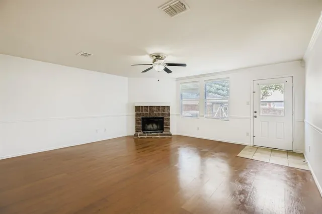 an empty room with windows fireplace and wooden floor