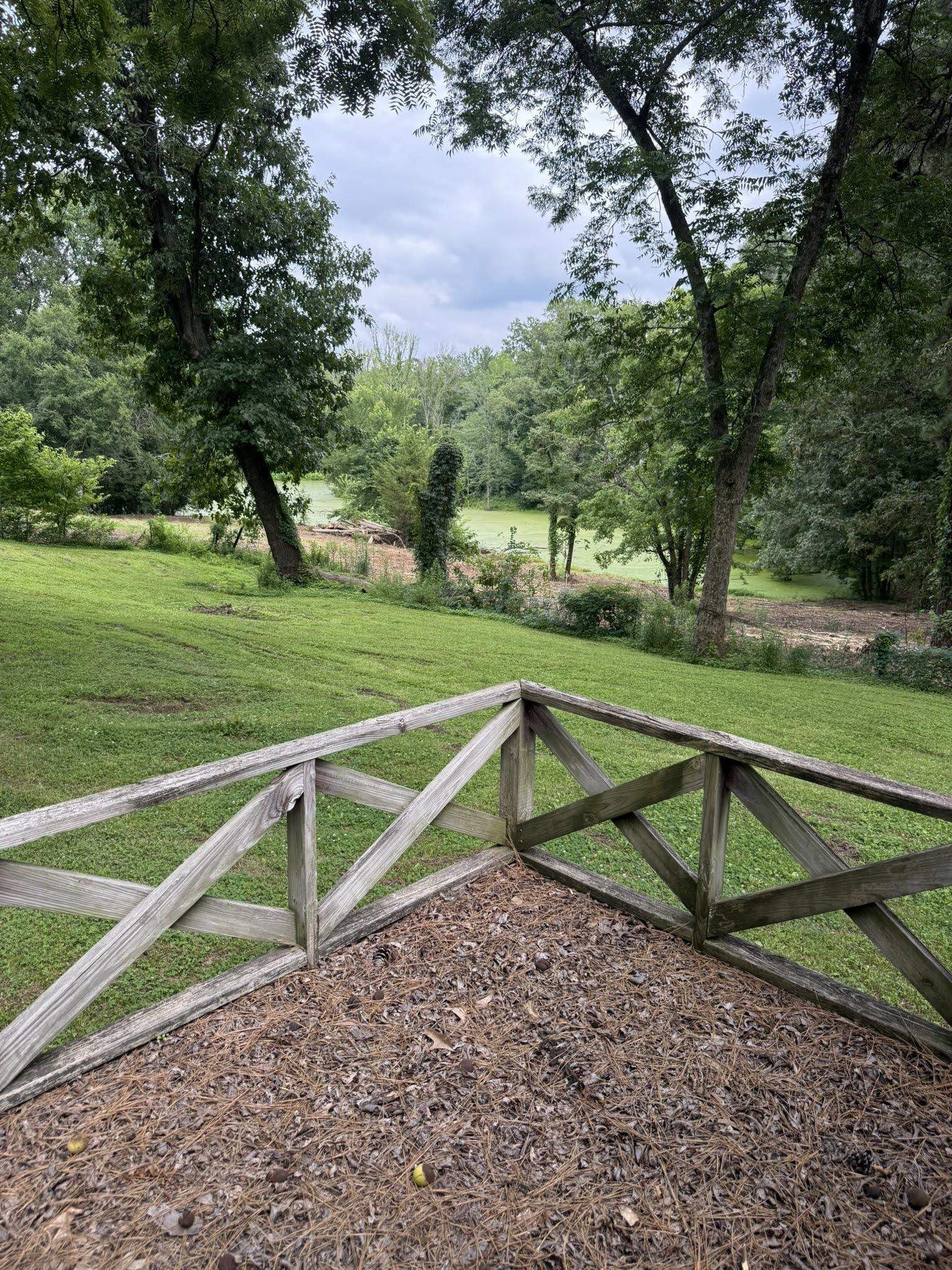 6760 Locke Road Millington, TN 38053 - Photo 39 of 39 Terraced outdoor area with natural wood railing, overlooking a verdant landscape with mature trees and a tranquil water feature