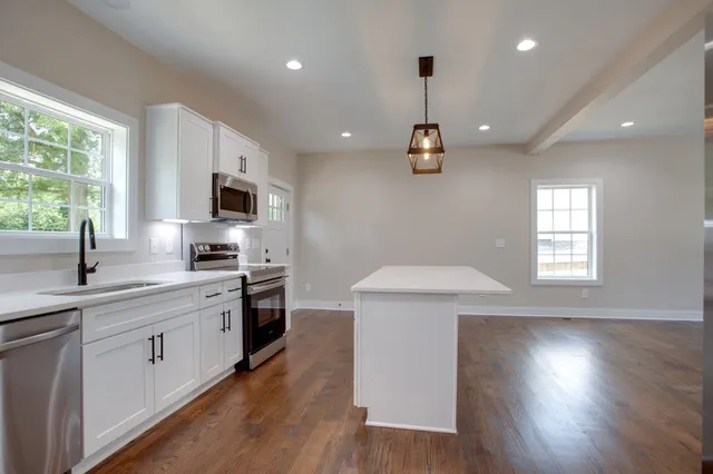 a kitchen with a sink a window stainless steel appliances and cabinets