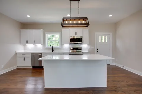 a kitchen with kitchen island stainless steel appliances a stove and a wooden floor