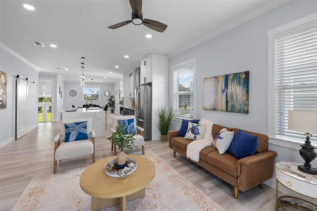 a living room with furniture potted plant and kitchen view