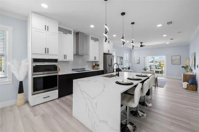 a kitchen with stainless steel appliances kitchen island granite countertop a stove a sink a refrigerator and white cabinets with wooden floor