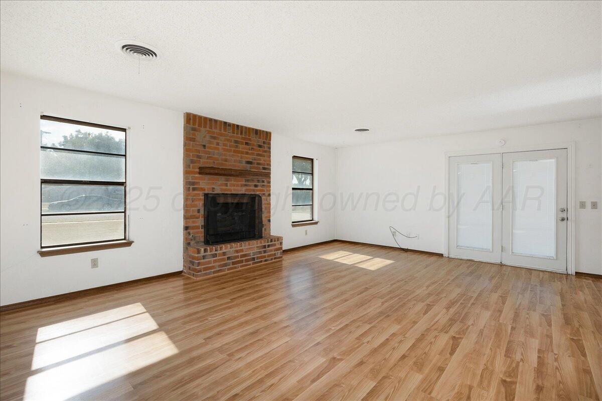 7210 Hatton Road Amarillo, TX 79110 - Photo 5 of 23 an empty room with wooden floor fireplace and windows