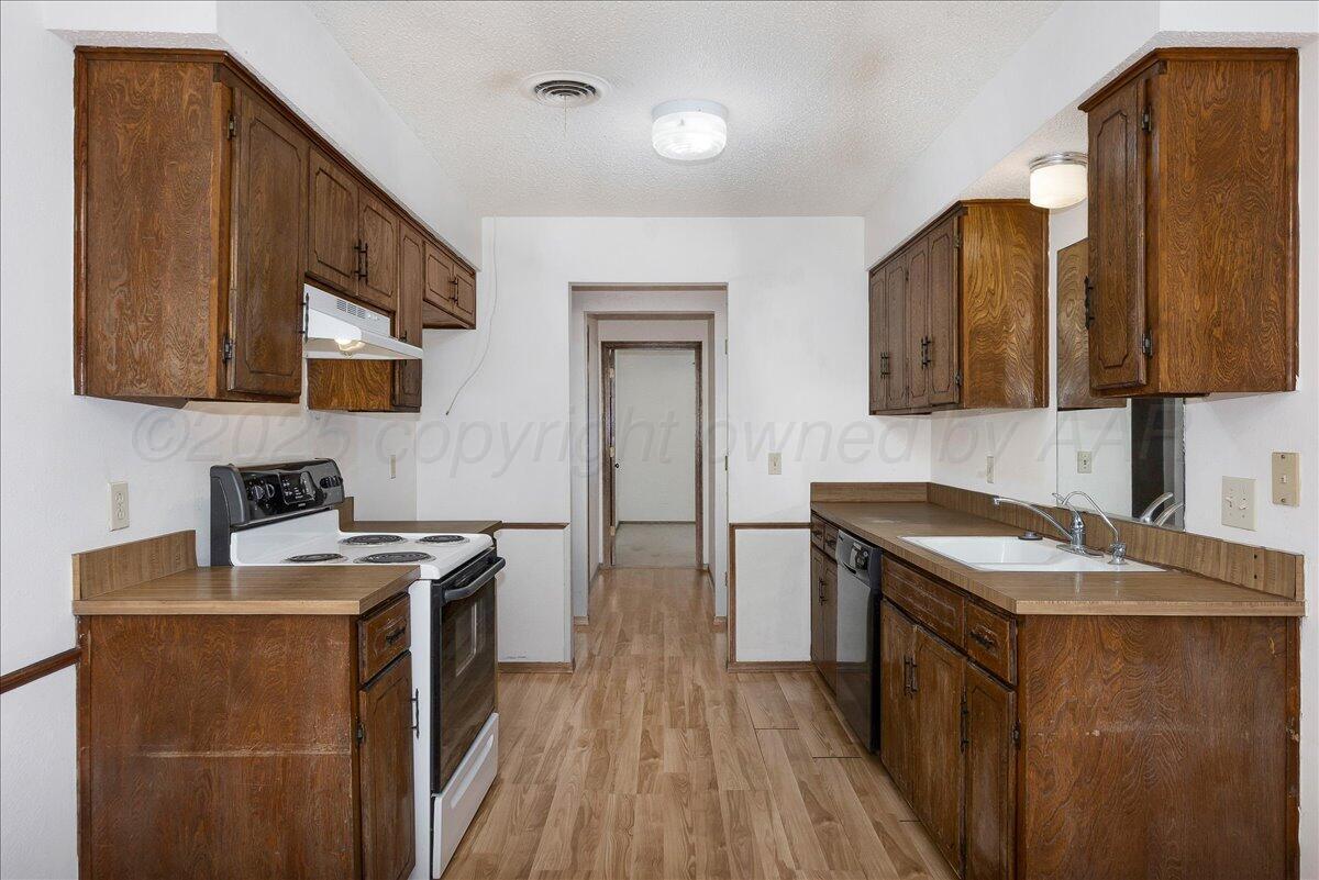 7210 Hatton Road Amarillo, TX 79110 - Photo 9 of 23 a kitchen that has a sink a stove and a wooden floor