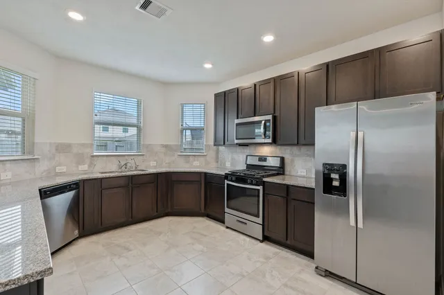 a kitchen with stainless steel appliances granite countertop a refrigerator stove a sink dishwasher and microwave