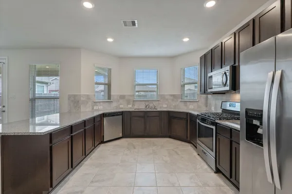 a large kitchen with stainless steel appliances granite countertop a refrigerator and a sink