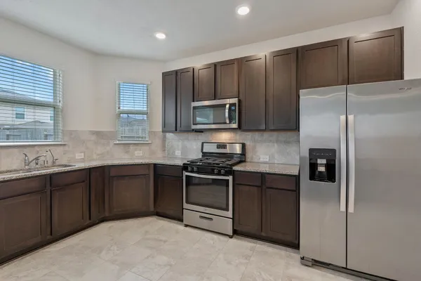 a kitchen with stainless steel appliances granite countertop a refrigerator stove a sink and dishwasher