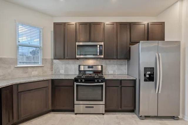 a kitchen with granite countertop a refrigerator stove and microwave