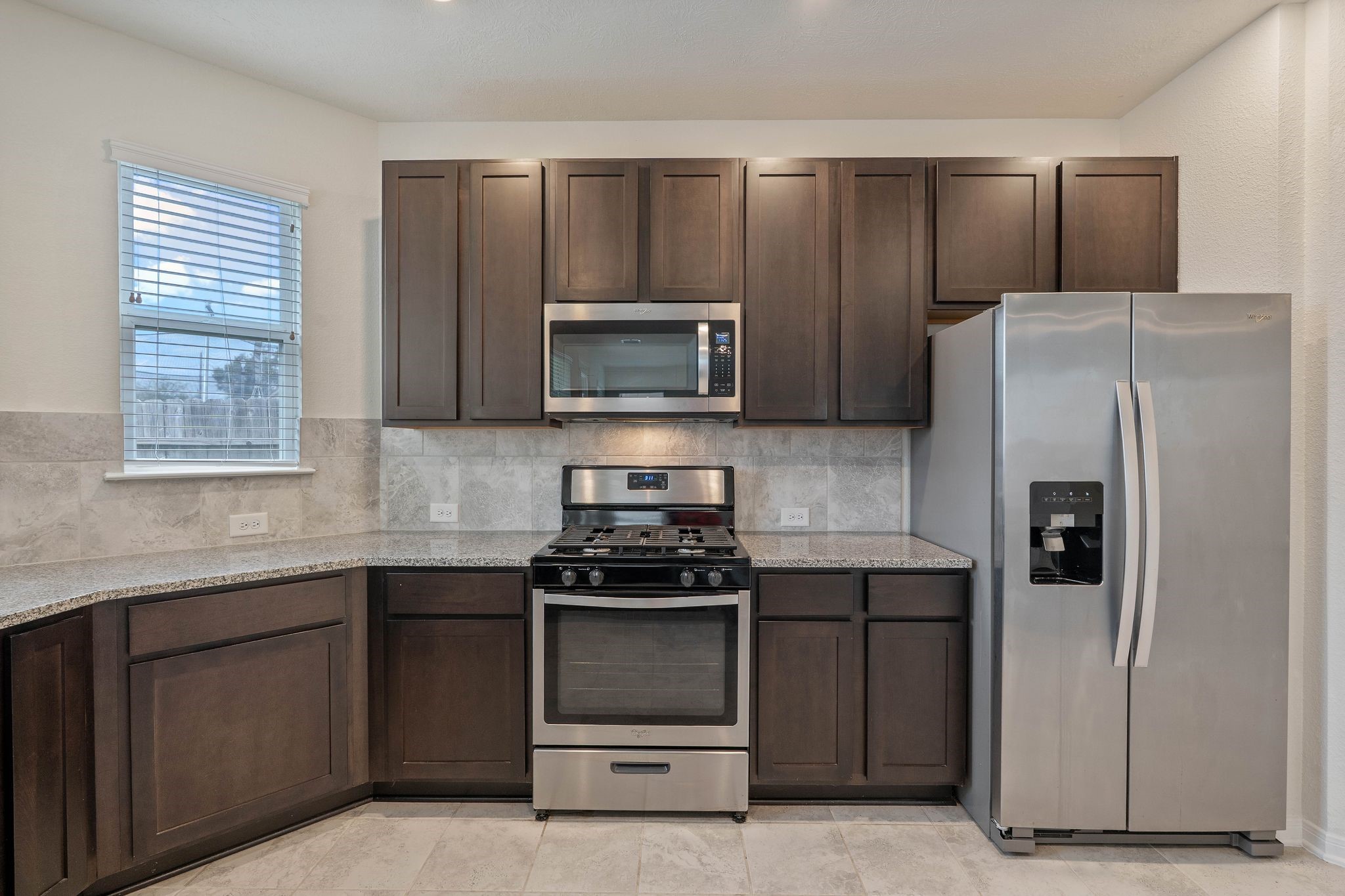 16623 Cliff Vale Court Houston, TX 77084 - Photo 15 of 34 a kitchen with granite countertop a refrigerator stove and microwave