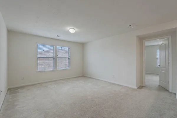 a view of an empty room with a window and bathroom