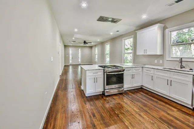 a kitchen with wooden floors and white stainless steel appliances
