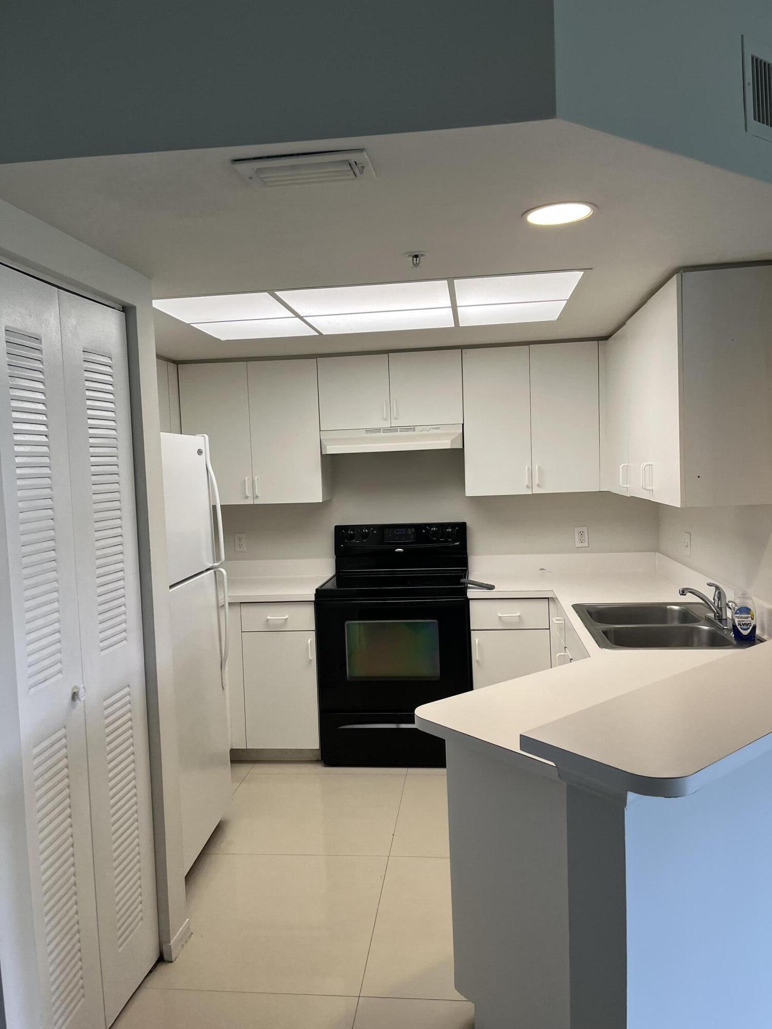 4191 Haverhill Road, Unit 409 West Palm Beach, FL 33417 - Photo 3 of 17 a kitchen with a stove and a refrigerator