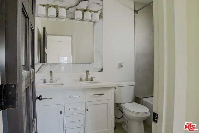 a bathroom with a toilet sink vanity and mirror
