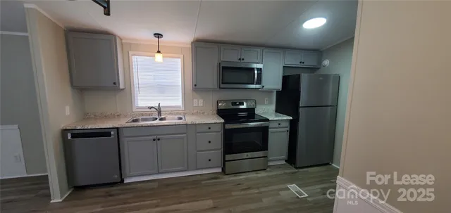 a kitchen with stainless steel appliances a sink cabinets and a wooden floor