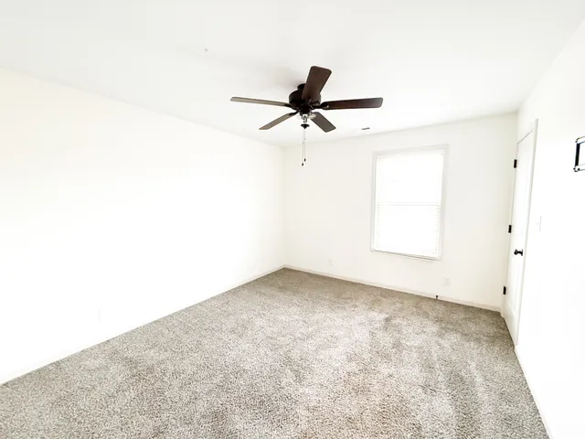 an empty room with a window and a fan