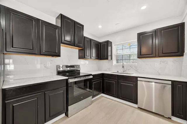 a kitchen with stainless steel appliances granite countertop wooden cabinets a stove top oven a sink and dishwasher