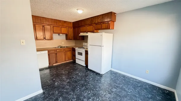 a kitchen with stainless steel appliances granite countertop a refrigerator a stove and a sink with wooden cabinets