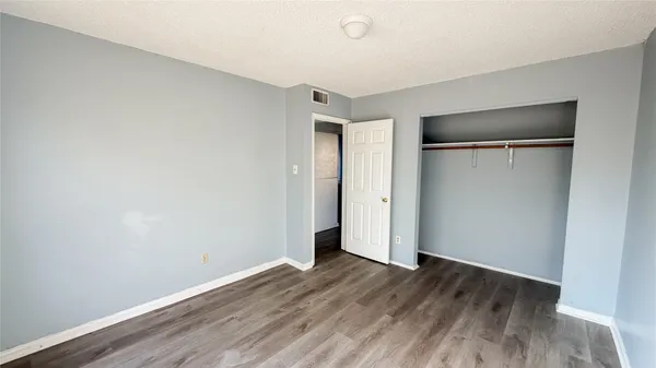 a view of an empty room with wooden floor and closet