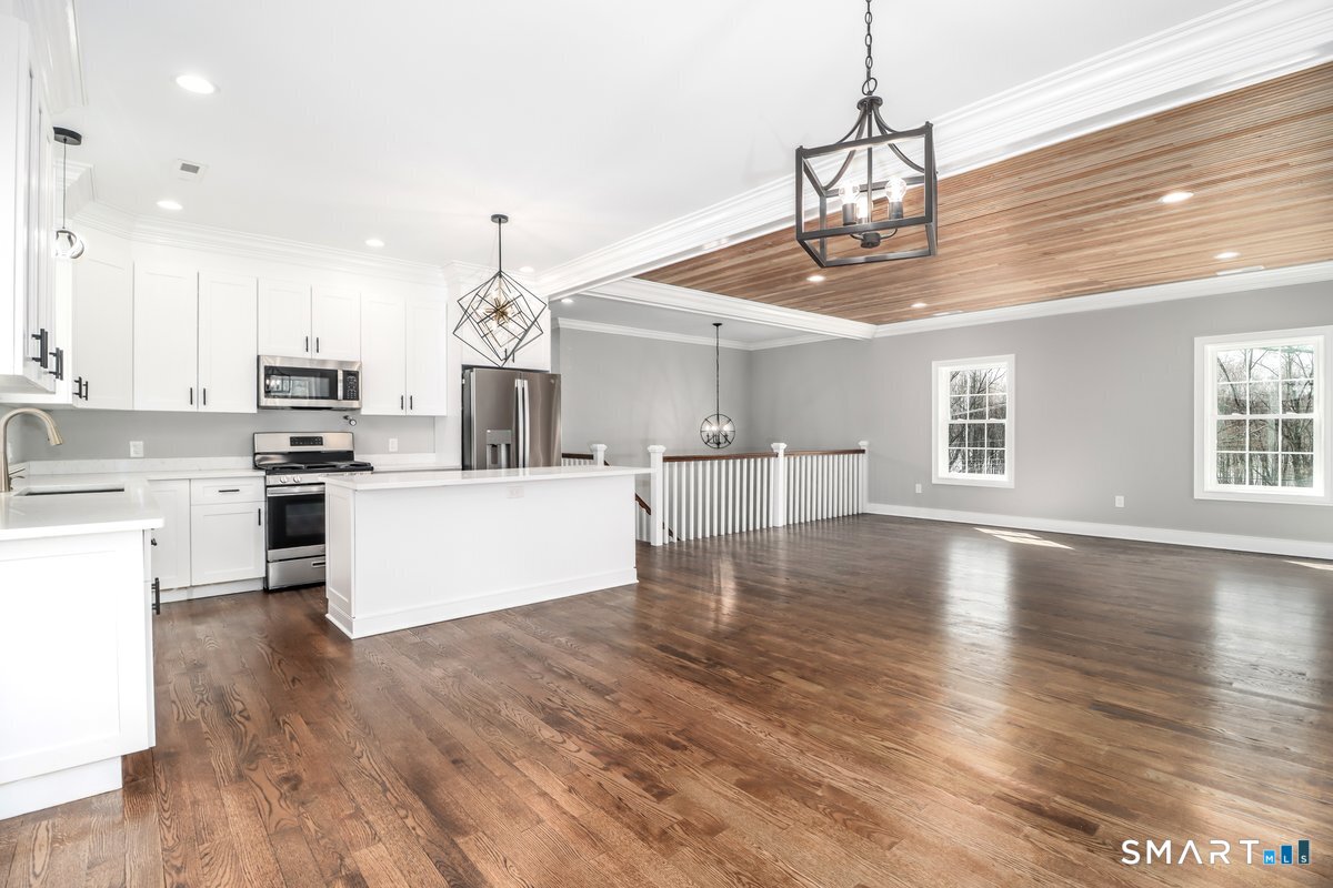 53 Pembroke Road Danbury, CT 06811 - Photo 11 of 37 a large kitchen with kitchen island a stove a sink dishwasher a microwave oven and a dining table with wooden floor
