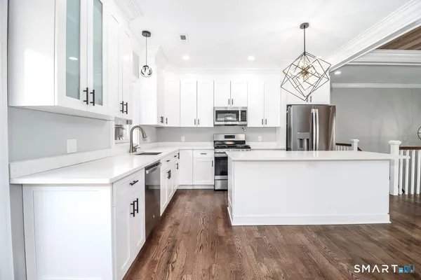 a kitchen with kitchen island granite countertop a sink a counter top space stainless steel appliances and cabinets