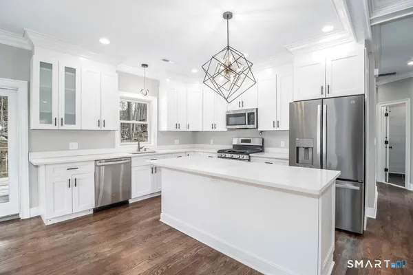 a kitchen with a sink stainless steel appliances a window and a chandelier