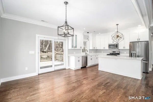 a large kitchen with kitchen island a stove a sink a center island and wooden floor