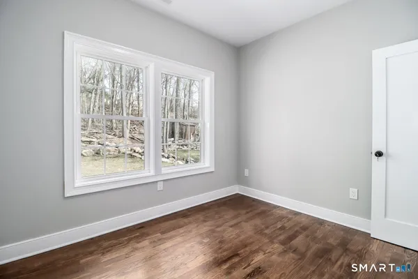 a view of an empty room with wooden floor and a window