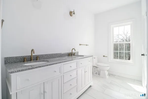 a bathroom with a granite countertop sink and a toilet