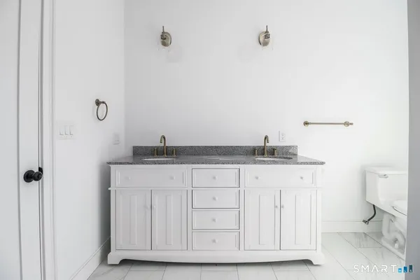 a bathroom with a granite countertop sink and a toilet