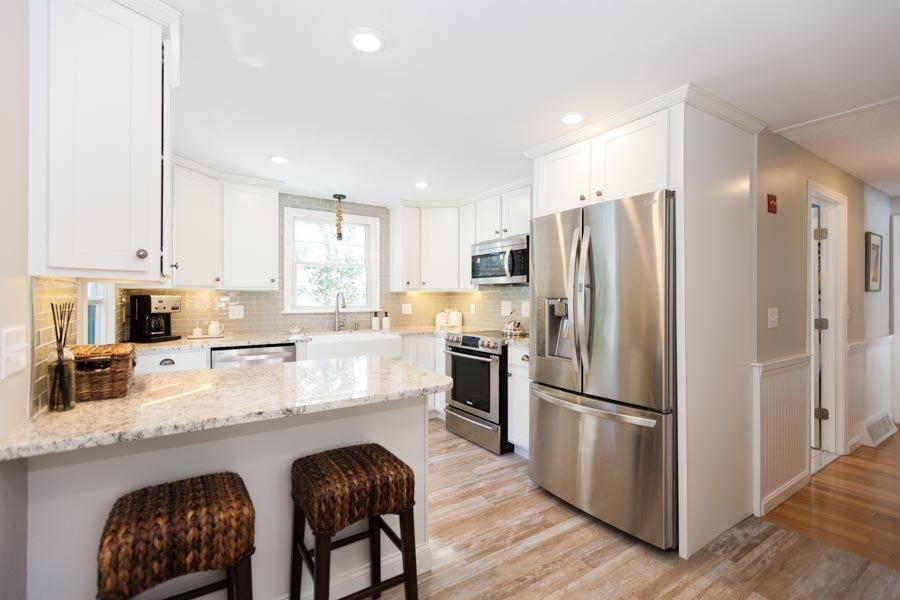 11 Cotuit Cove Road Cotuit, MA 02635 - Photo 8 of 35 a kitchen with stainless steel appliances granite countertop a refrigerator a stove a sink a dining table and chairs with wooden floor