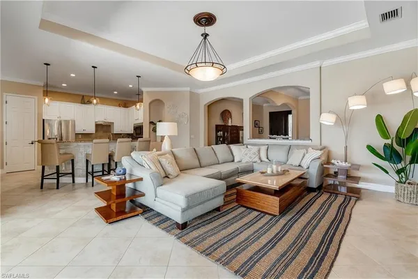 a living room with furniture kitchen view and a chandelier